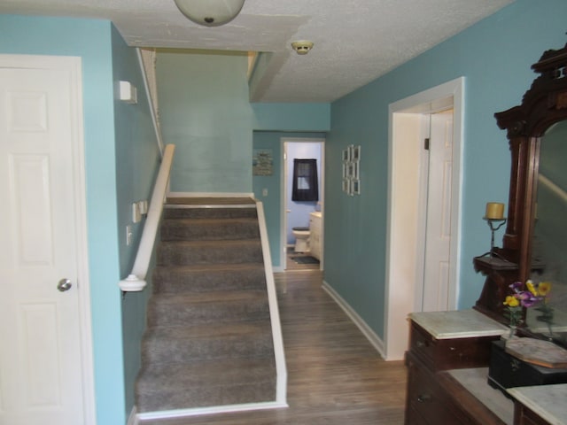 staircase featuring a textured ceiling and wood-type flooring