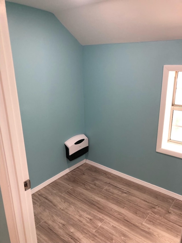 spare room featuring baseboards, wood finished floors, and lofted ceiling