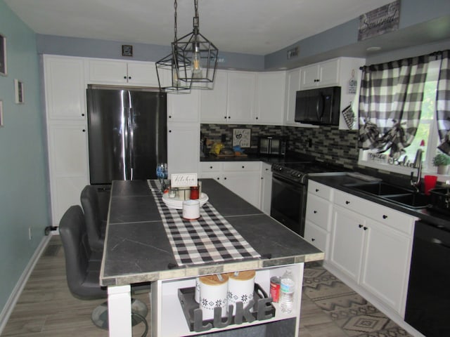 kitchen featuring white cabinets, tasteful backsplash, a kitchen island, black appliances, and sink