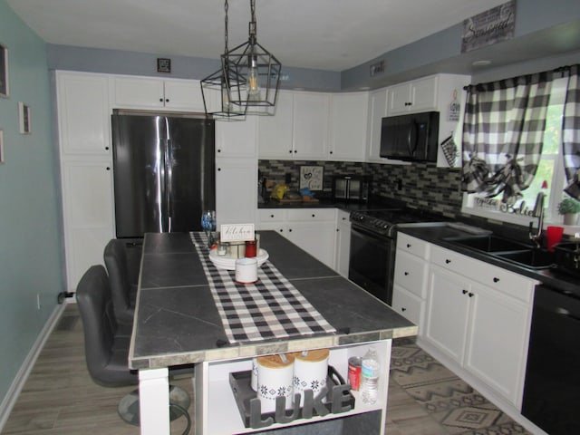 kitchen with a sink, decorative backsplash, black appliances, and white cabinetry