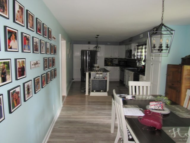 dining room featuring baseboards, wood finished floors, and a notable chandelier
