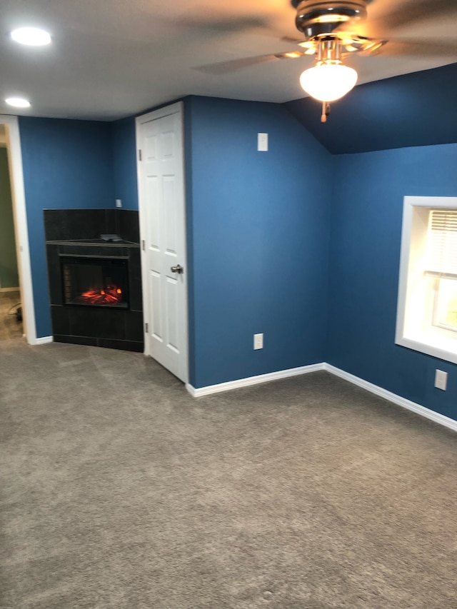 interior space featuring ceiling fan, vaulted ceiling, and a tile fireplace