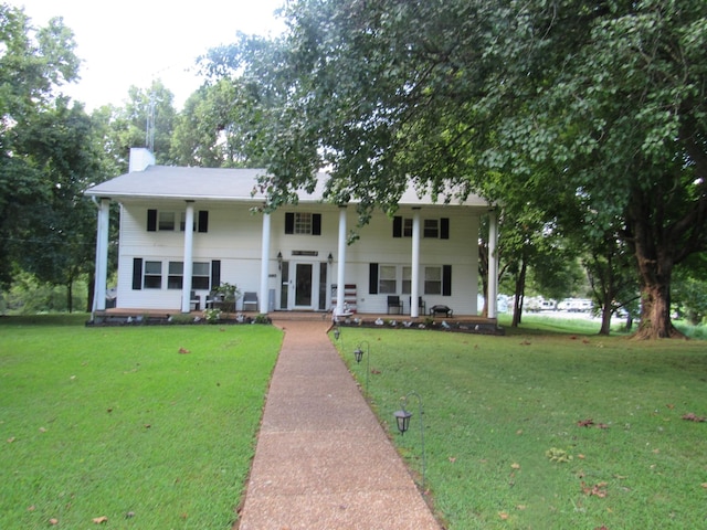 neoclassical home featuring covered porch, a chimney, and a front lawn