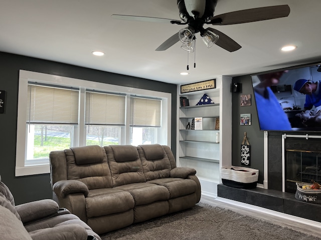 living room featuring hardwood / wood-style floors, a tiled fireplace, and ceiling fan