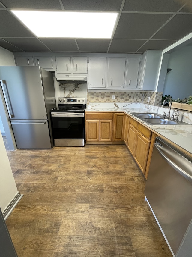 kitchen featuring decorative backsplash, a paneled ceiling, hardwood / wood-style flooring, sink, and stainless steel appliances