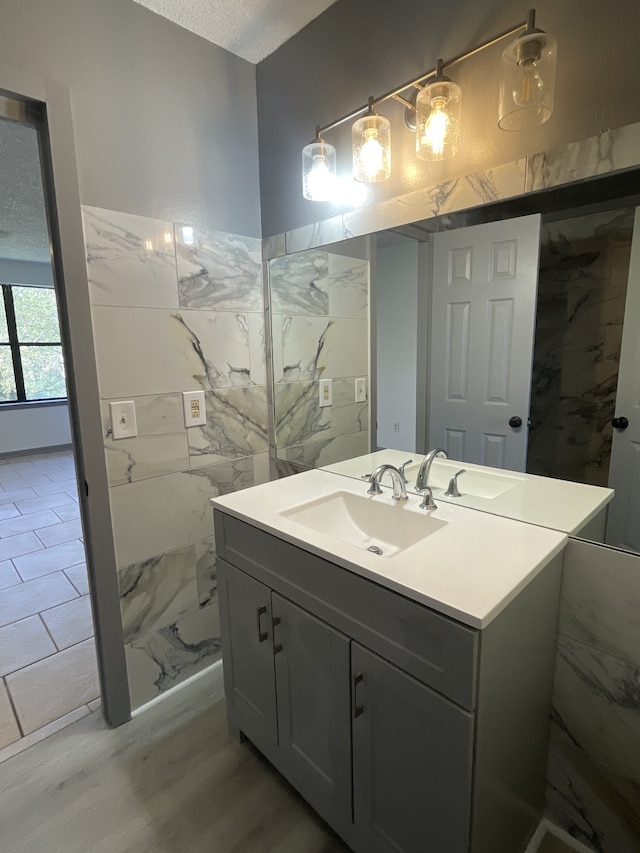 bathroom featuring vanity, hardwood / wood-style flooring, a textured ceiling, and tile walls