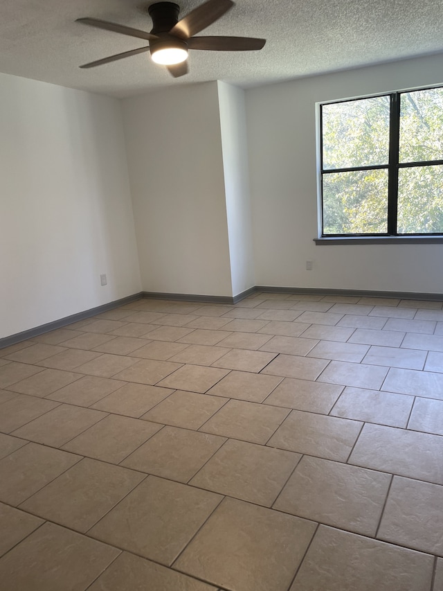 tiled spare room with a textured ceiling and ceiling fan