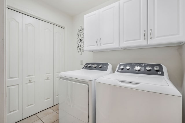 laundry area with light tile patterned flooring, washer and dryer, and cabinets