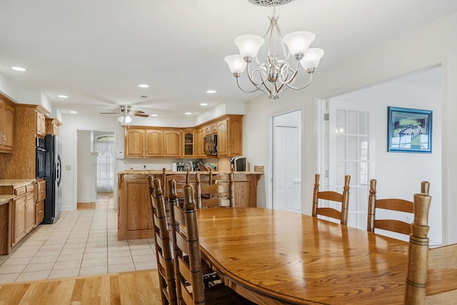 dining room with light hardwood / wood-style flooring and ceiling fan with notable chandelier