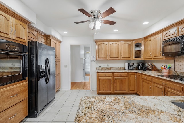 kitchen with light stone countertops, ceiling fan, black appliances, and light tile patterned flooring