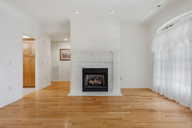 unfurnished living room with ornamental molding, a fireplace, and light wood-type flooring