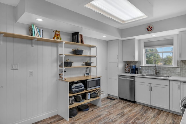 kitchen featuring appliances with stainless steel finishes, light wood-type flooring, backsplash, and sink