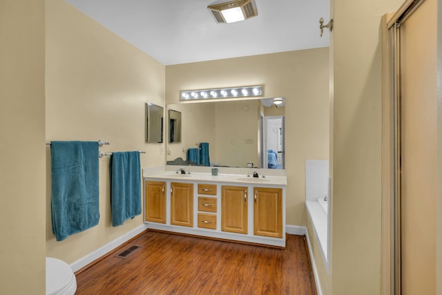 bathroom featuring hardwood / wood-style flooring, vanity, toilet, and a tub to relax in