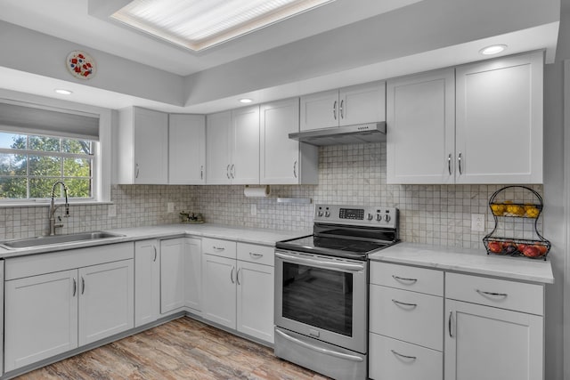 kitchen featuring light stone countertops, light wood-type flooring, backsplash, stainless steel electric stove, and sink