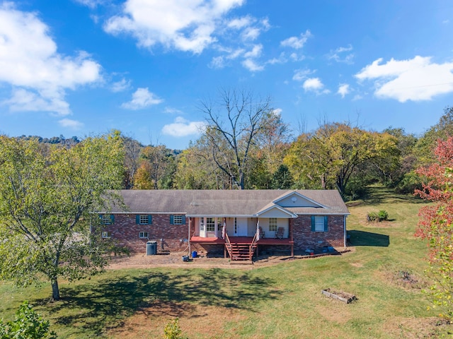 ranch-style home with central air condition unit, a wooden deck, and a front lawn