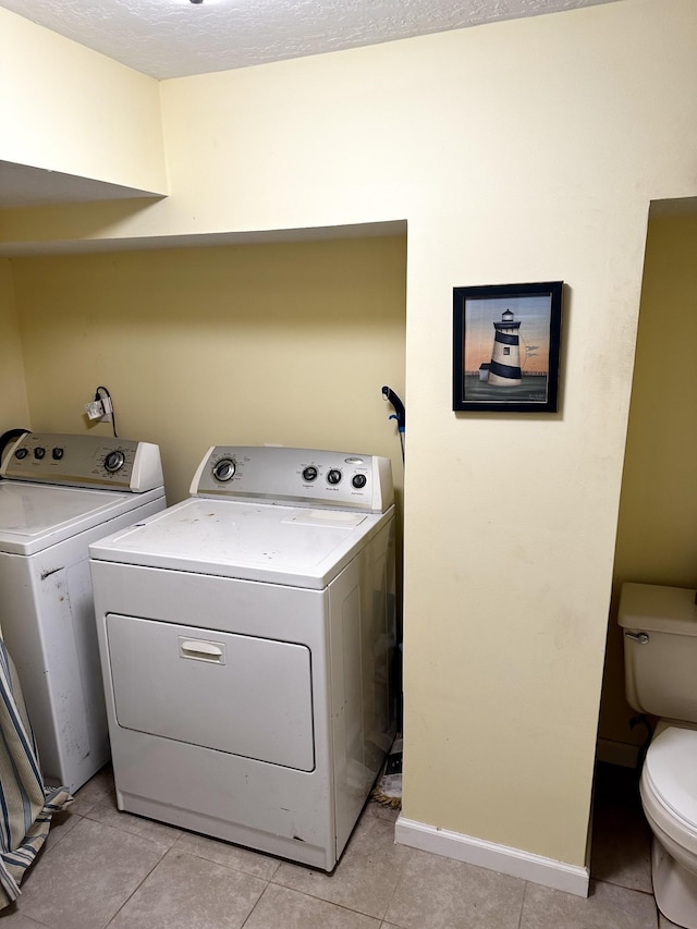 clothes washing area with light tile patterned flooring and washing machine and dryer