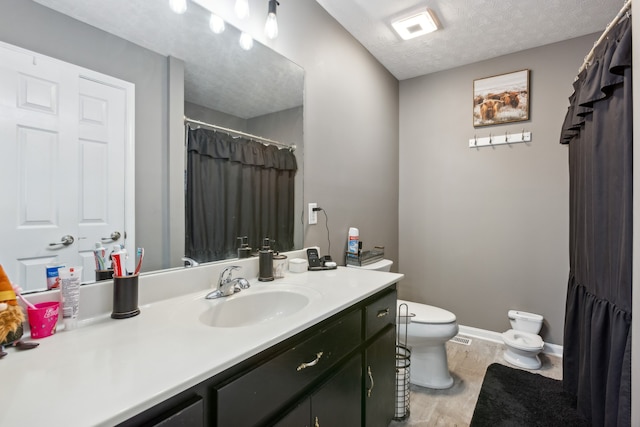 bathroom featuring toilet, a textured ceiling, hardwood / wood-style flooring, and vanity