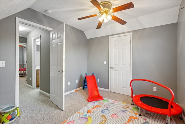 playroom with ceiling fan, light carpet, and lofted ceiling