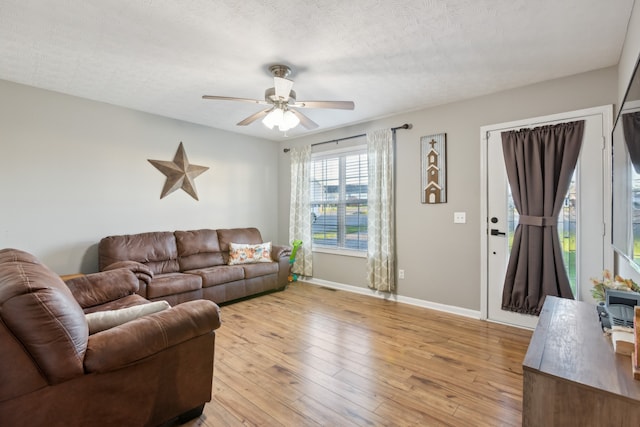 living room with light hardwood / wood-style floors, a textured ceiling, and ceiling fan