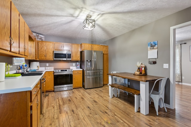 kitchen featuring appliances with stainless steel finishes, light hardwood / wood-style flooring, and a textured ceiling