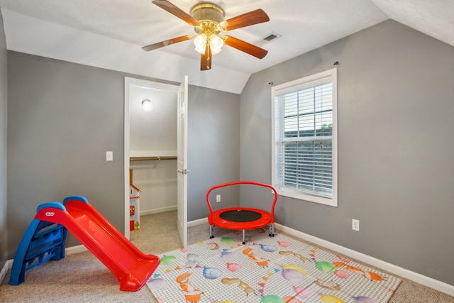 recreation room with ceiling fan, carpet flooring, and vaulted ceiling