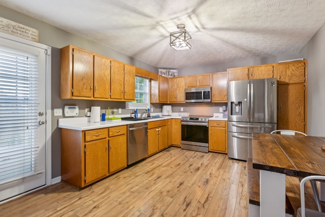 kitchen featuring appliances with stainless steel finishes, light hardwood / wood-style flooring, and a textured ceiling