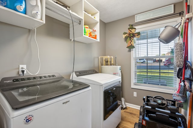 clothes washing area with a textured ceiling, light hardwood / wood-style flooring, and separate washer and dryer