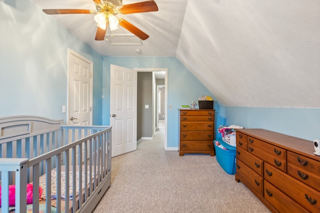 carpeted bedroom featuring a nursery area, a textured ceiling, vaulted ceiling, and ceiling fan