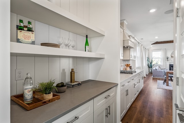 bar with white cabinets, dark hardwood / wood-style flooring, stainless steel gas stovetop, premium range hood, and tasteful backsplash