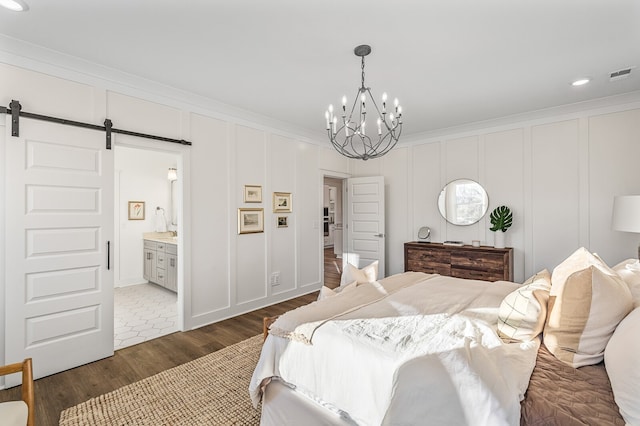 bedroom featuring a barn door, ensuite bath, ornamental molding, a chandelier, and dark hardwood / wood-style floors