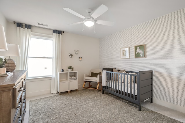 bedroom featuring a crib, carpet flooring, and ceiling fan