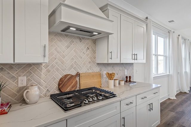 kitchen with stainless steel gas cooktop, dark wood-type flooring, custom range hood, and light stone countertops