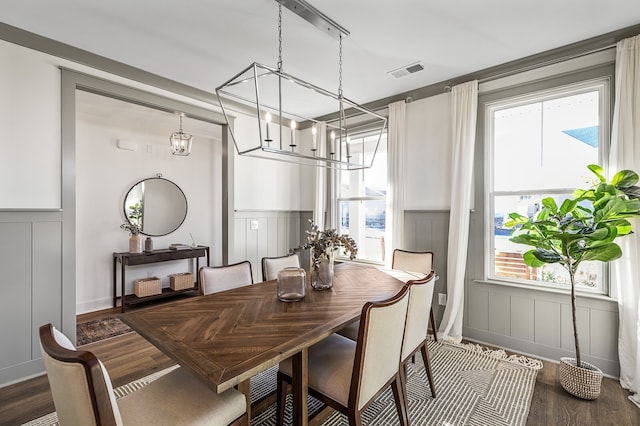 dining space featuring dark wood-type flooring, a wealth of natural light, and an inviting chandelier