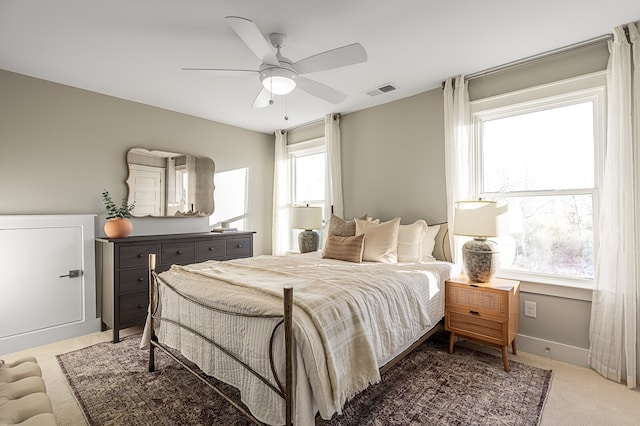 carpeted bedroom featuring multiple windows and ceiling fan