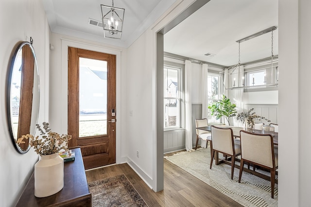 foyer entrance with crown molding, a notable chandelier, and dark hardwood / wood-style floors