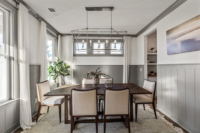 dining space with crown molding, wood-type flooring, a chandelier, and built in shelves