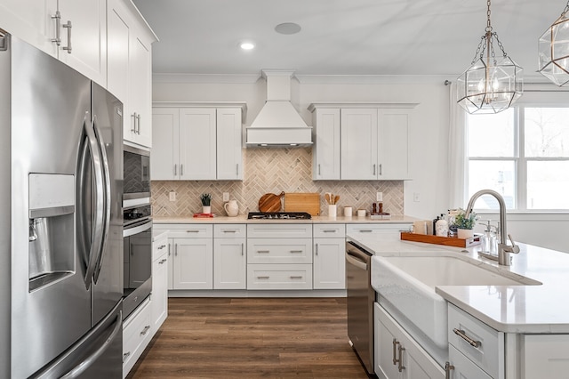 kitchen featuring hanging light fixtures, custom range hood, sink, white cabinetry, and appliances with stainless steel finishes