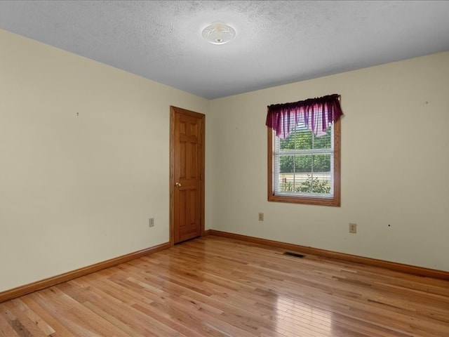 spare room featuring light hardwood / wood-style floors and a textured ceiling