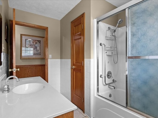 bathroom featuring vanity, combined bath / shower with glass door, a textured ceiling, and tile patterned flooring