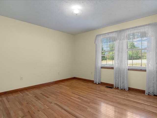 unfurnished room with a textured ceiling and light hardwood / wood-style flooring