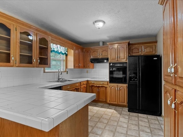 kitchen featuring tile countertops, black appliances, sink, and kitchen peninsula