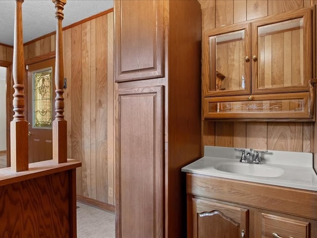 bathroom featuring vanity, wood walls, and a textured ceiling