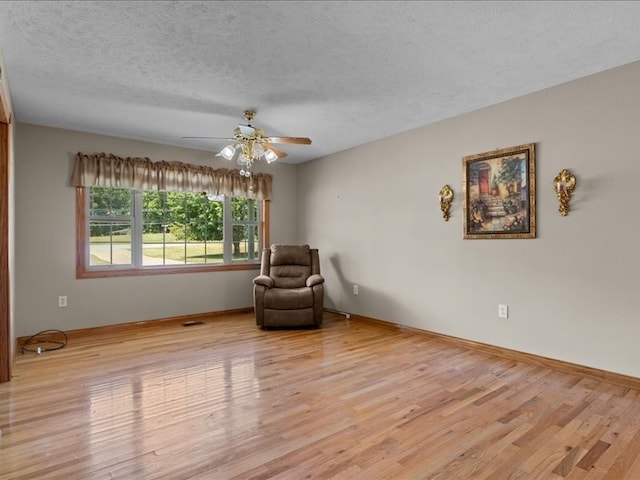 sitting room featuring light hardwood / wood-style floors, a textured ceiling, and ceiling fan