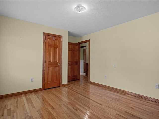 unfurnished room featuring light hardwood / wood-style flooring and a textured ceiling