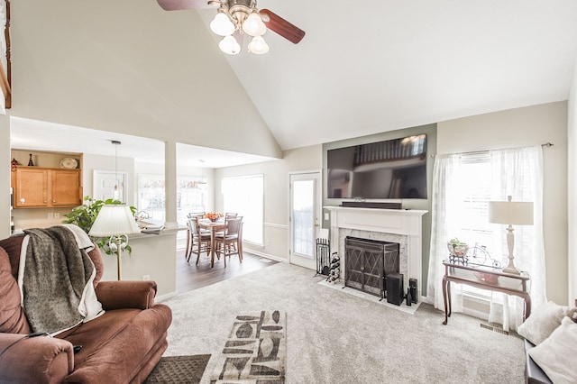 carpeted living room featuring high vaulted ceiling, a healthy amount of sunlight, and a fireplace