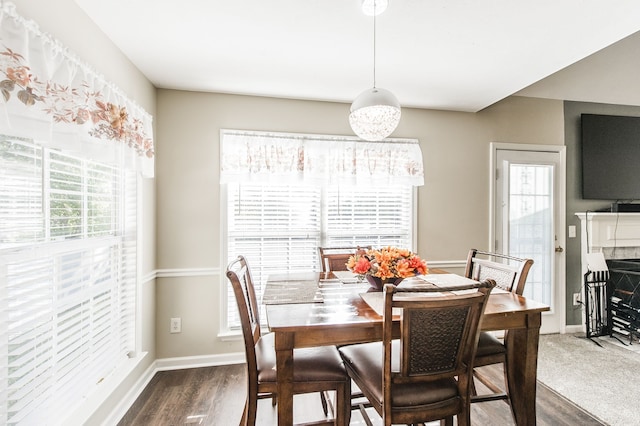 dining area with dark hardwood / wood-style floors, a tiled fireplace, and a wealth of natural light