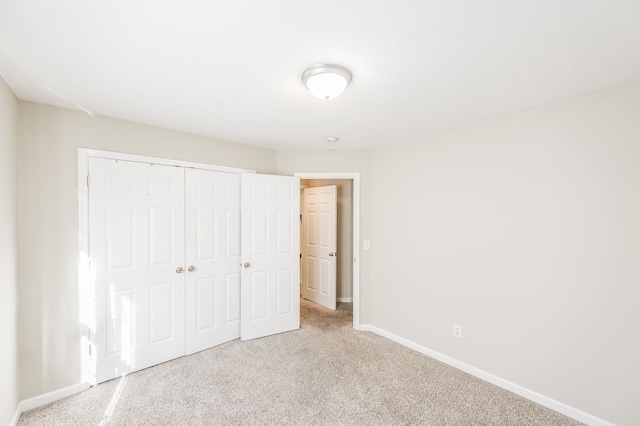 unfurnished bedroom featuring a closet and light colored carpet