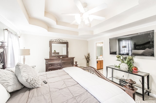 bedroom with ceiling fan, a raised ceiling, and ensuite bath