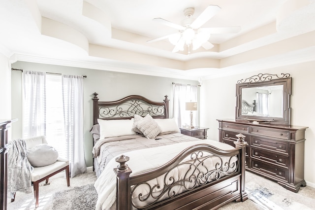 bedroom with crown molding, light carpet, a tray ceiling, and ceiling fan