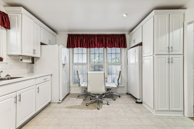 kitchen with tasteful backsplash, sink, white refrigerator, and white cabinets